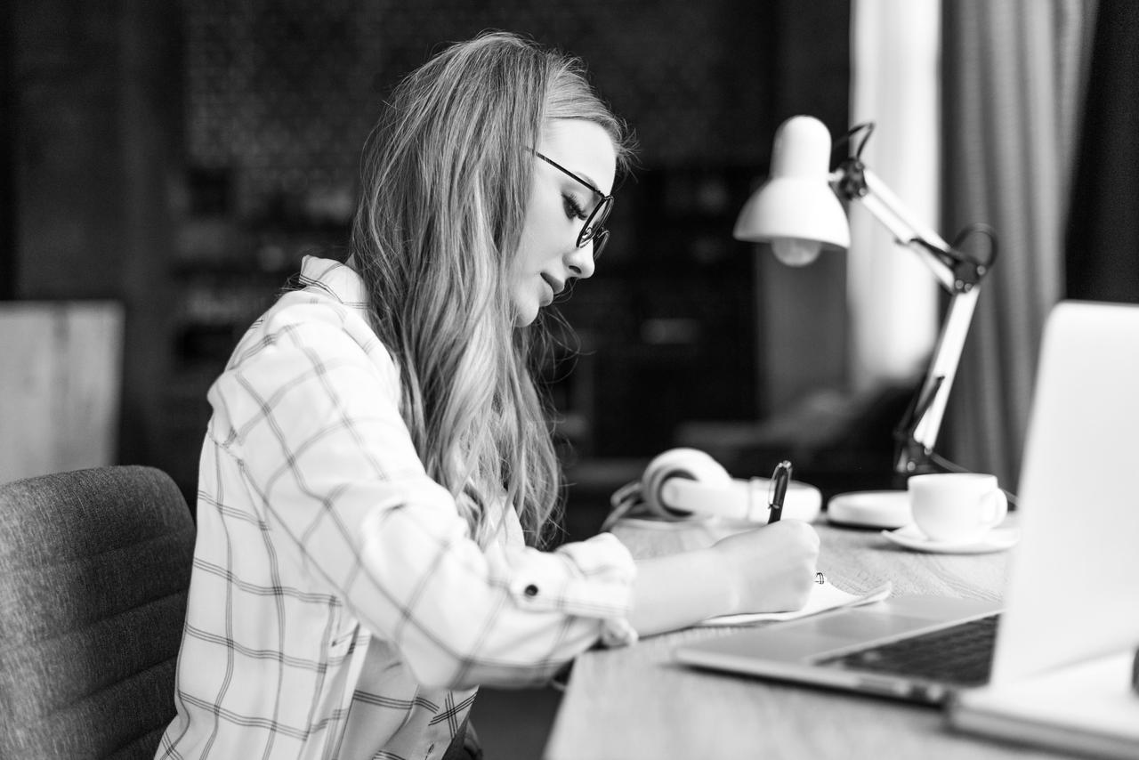 Young woman writing in notebook at workplace