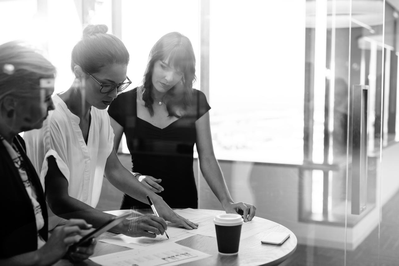 Group of businesswomen standing at the table and discussing new strategies.