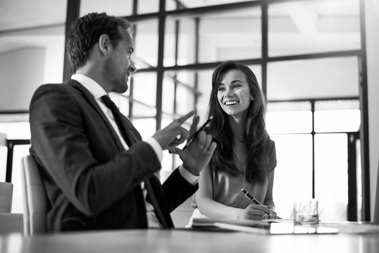 A man and woman sitting at a table collaborating in the workplace