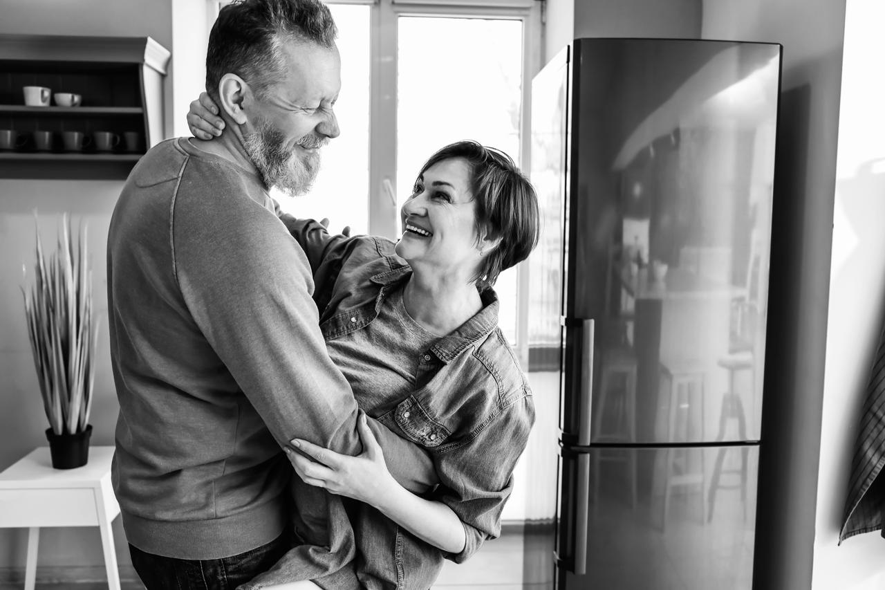 Smiling couple standing up and hugging in the kitchen