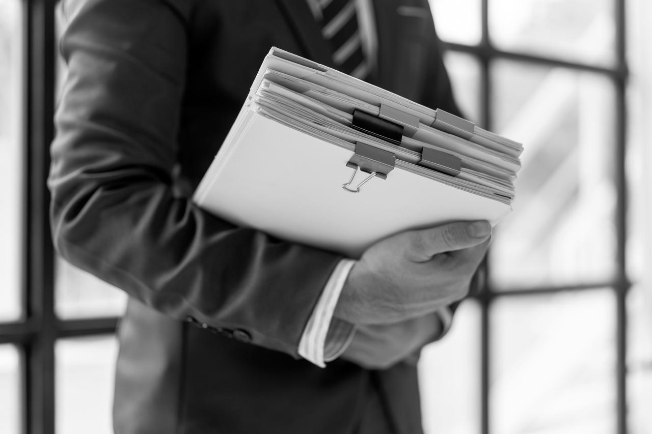 A man holding a stack of files in his arm